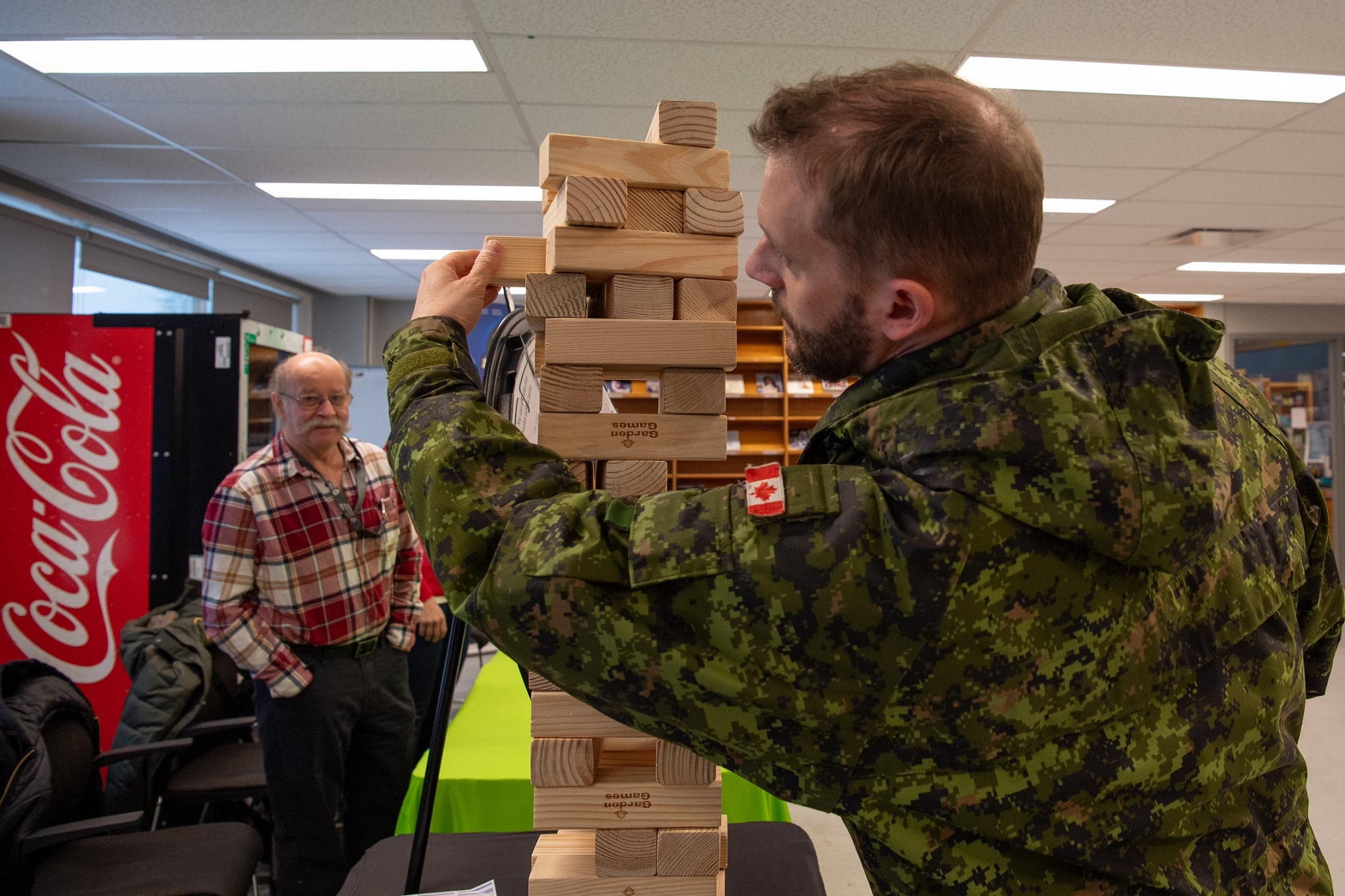 Un membre des Forces canadiennes joue au jeu Jenga, avec un membre du personnel qui regarde en arrière-plan