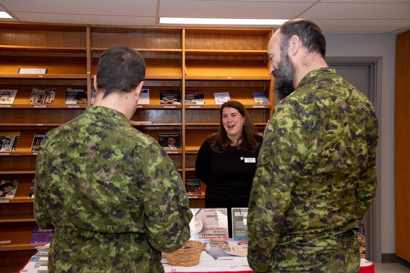 Un membre du personnel parle à deux membres des Forces canadiennes des services offerts au CRFMK