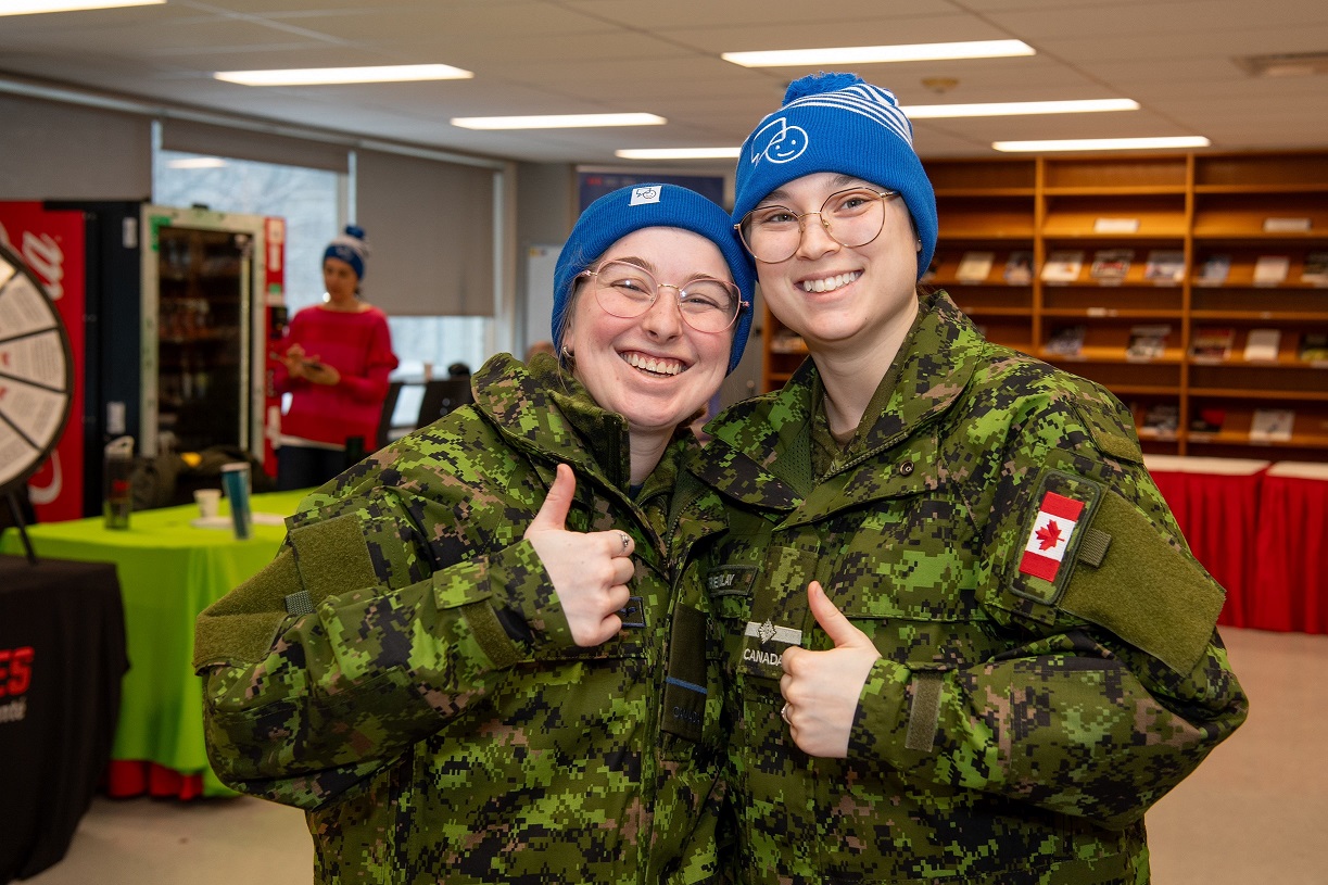 Two cadets smiling as they show off their new toques