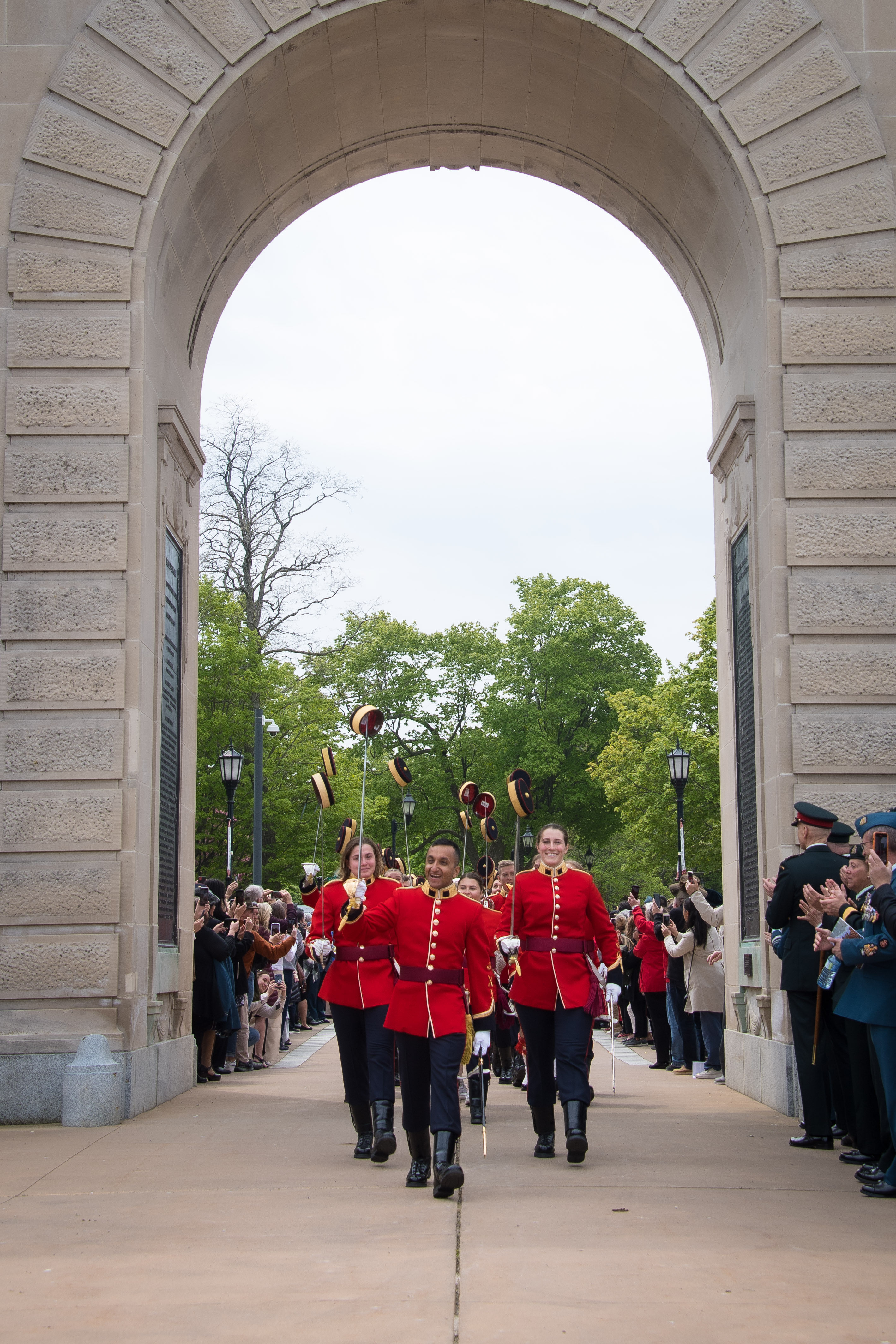 Le commandant de l'escadre des élofs mène le cortège des aspm/élof de quatrième année qui ont reçu leur brevet d’officier, défilant sous l'arc commémoratif sur le campus, sous le regard du public.