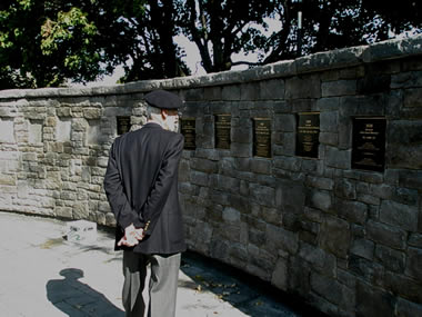 Un ancien élève-officier, membre de la Vieille Brigade, lisant des plaques de bronze sur le Mur