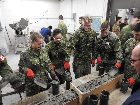 Structures Technician and Undergraduate Students pouring Concrete test cylinders/Technologue en structures et étudiants de premier cycle coulant des cylindres d'essai en béton